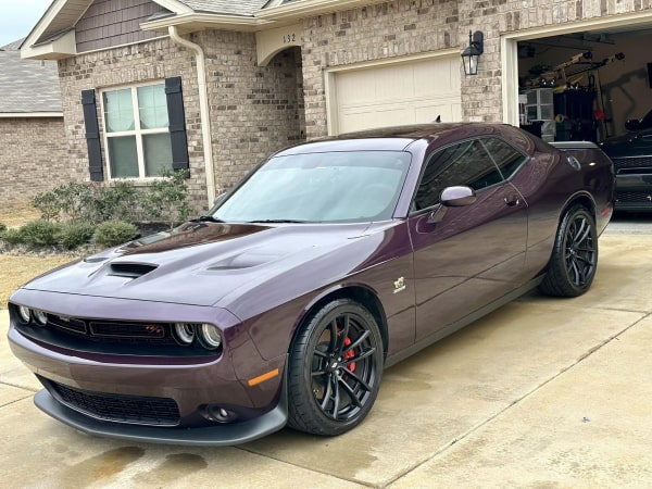 Green John Deere 5075E tractor with a front loader parked on a grassy lawn in front of a white house.