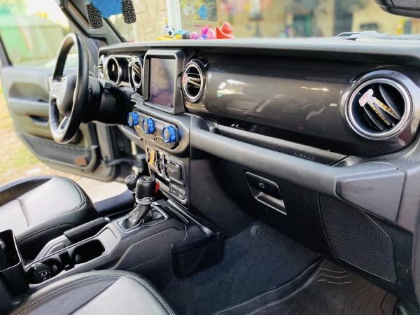Interior view of a car showing a black dashboard with central air vents, a multimedia screen, and climate control buttons.