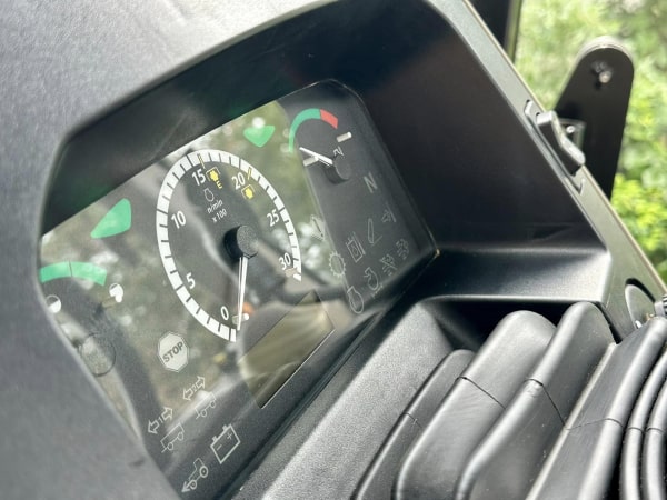 A white Forester RV with black and grey swirl decals parked on a sunny day, casting a shadow on the concrete ground.