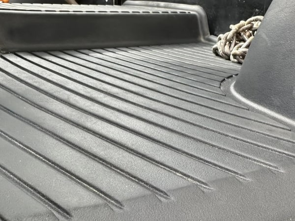 Close-up of a green tractor's dashboard displaying various gauges and control icons, with a blurred greenery background.